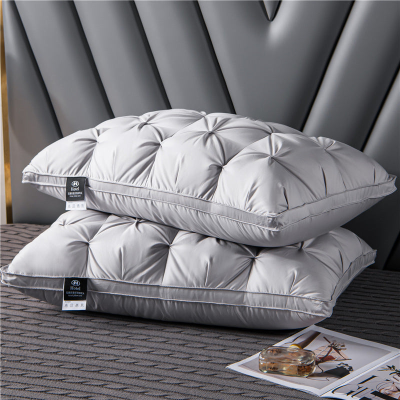 Two gray pillows stacked on a textured surface with a blurred background