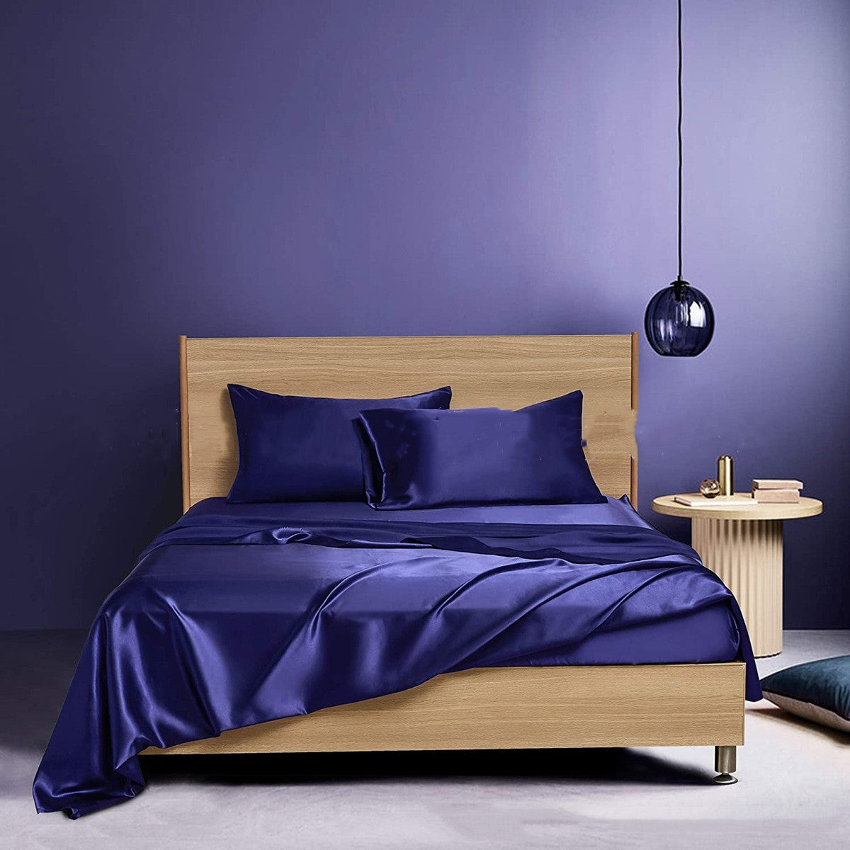 Bed with blue satin sheets and pillows against a purple wall.