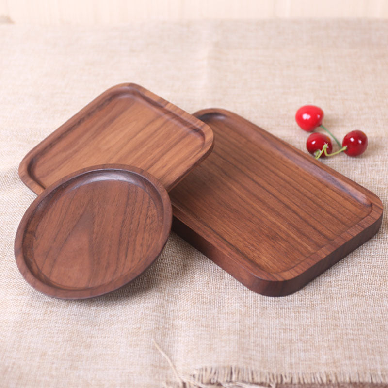 Three wooden trays on a textured beige surface with cherry tomatoes.