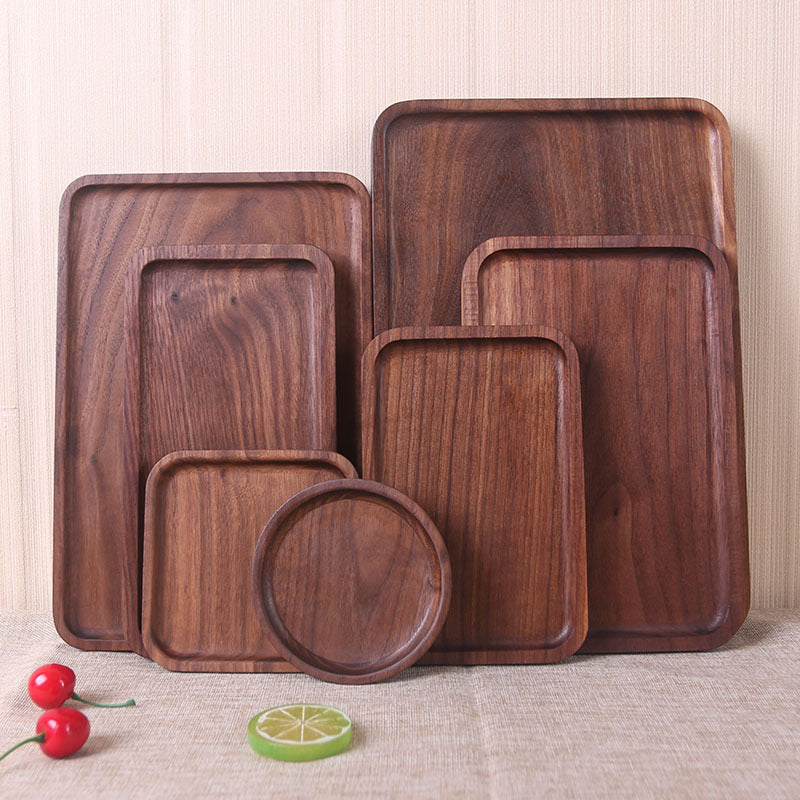 Set of wooden trays of different sizes on a textured surface with fruits and a lime.