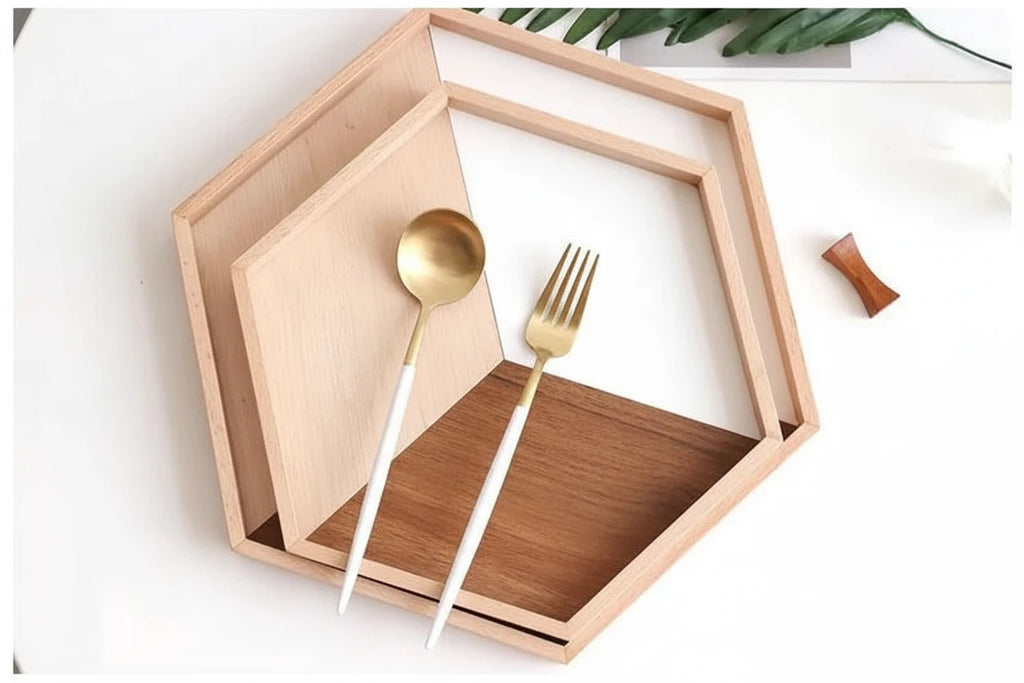 Wooden and metal cutlery set on a hexagonal wooden tray with a white background